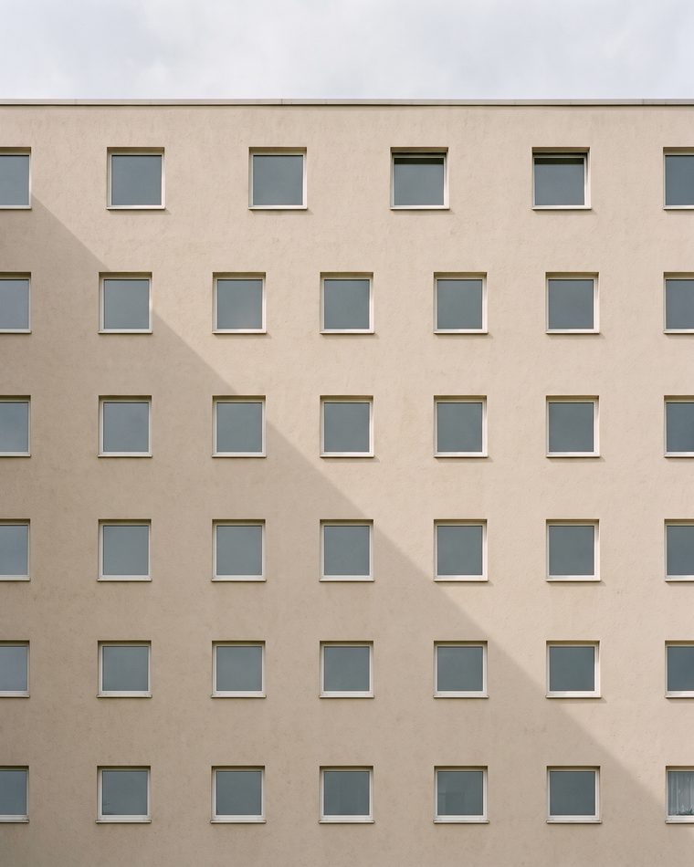 Raster gleichförmiger Fenster auf einer hellen Putzfassade